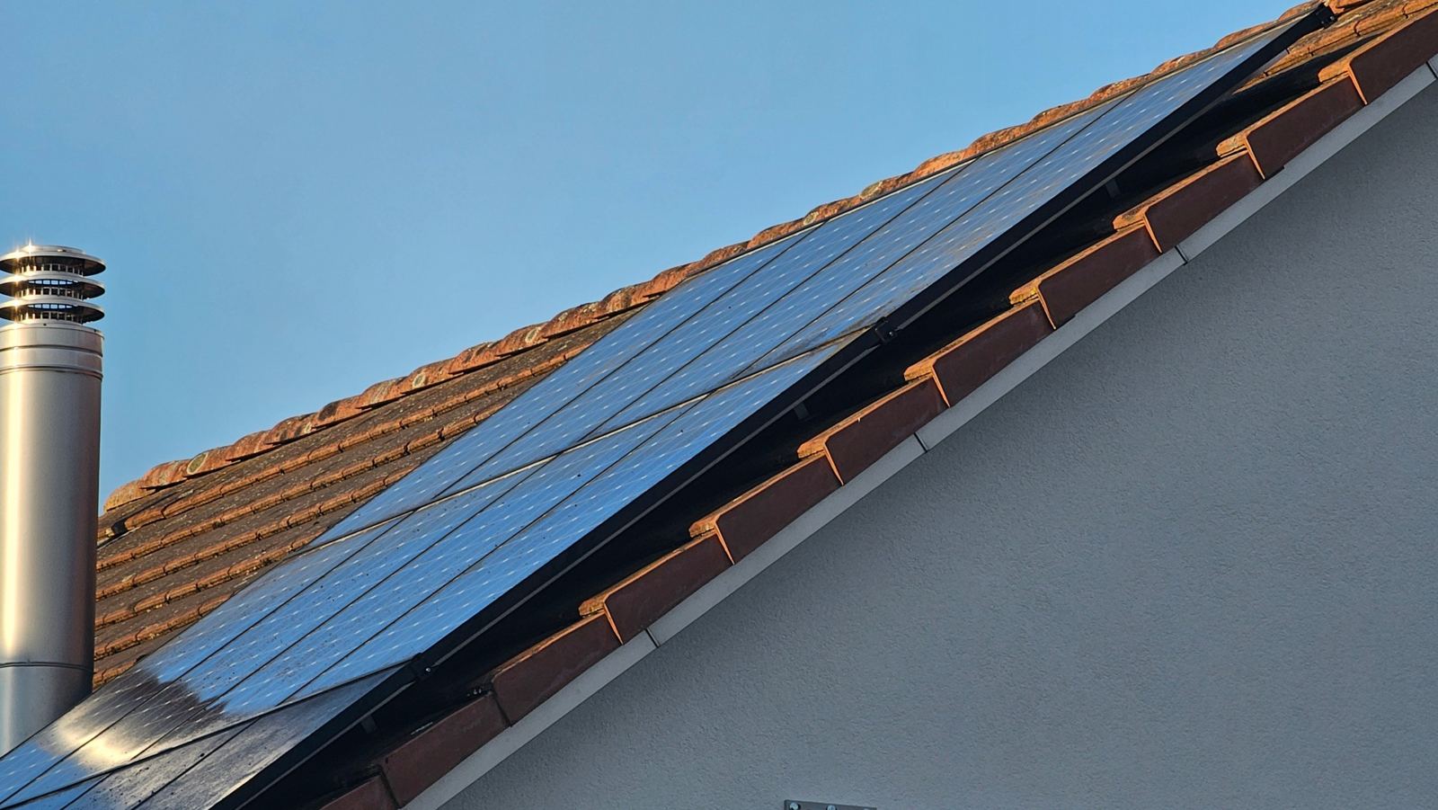 Bürste reinigt Solarmodule auf einem Ziegeldach
